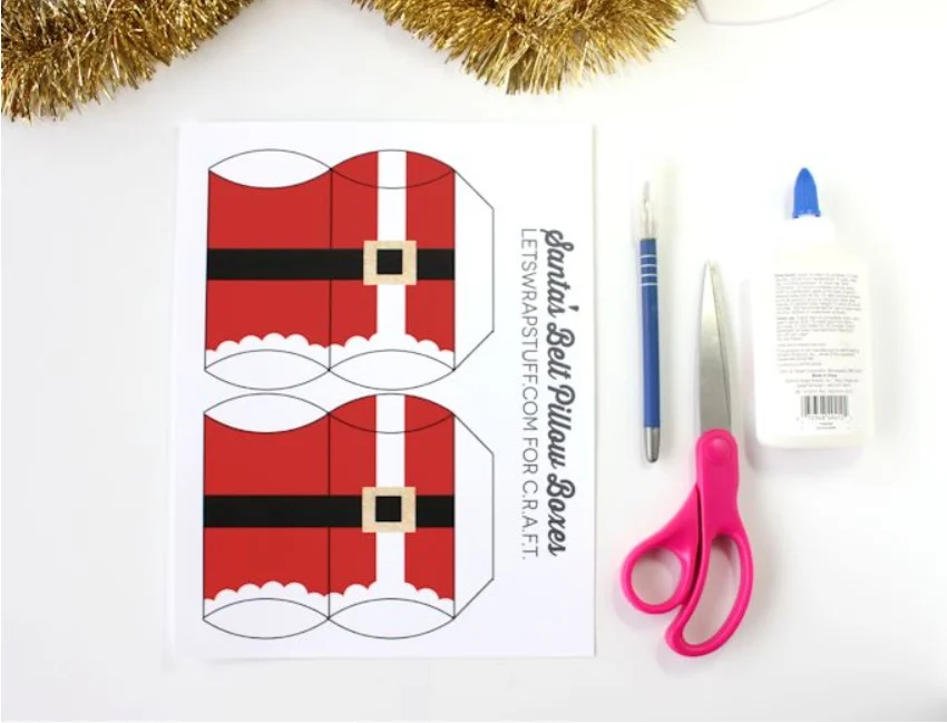 red santa pillow box with black belt printable next to scissors and glue