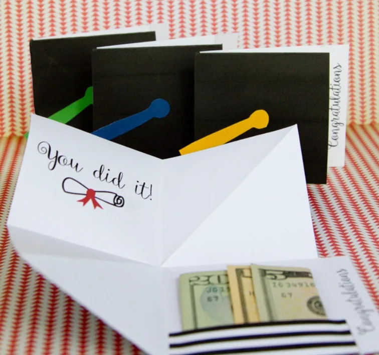 inside of pop up card saying "You did it" with cash tucked into black and white striped pocket