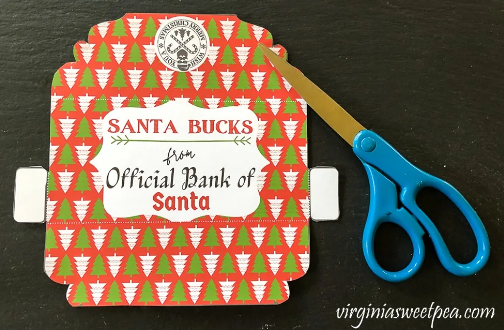 red envelope with green and white trees saying Santa Bucks from Official Bank of Santa on dark background