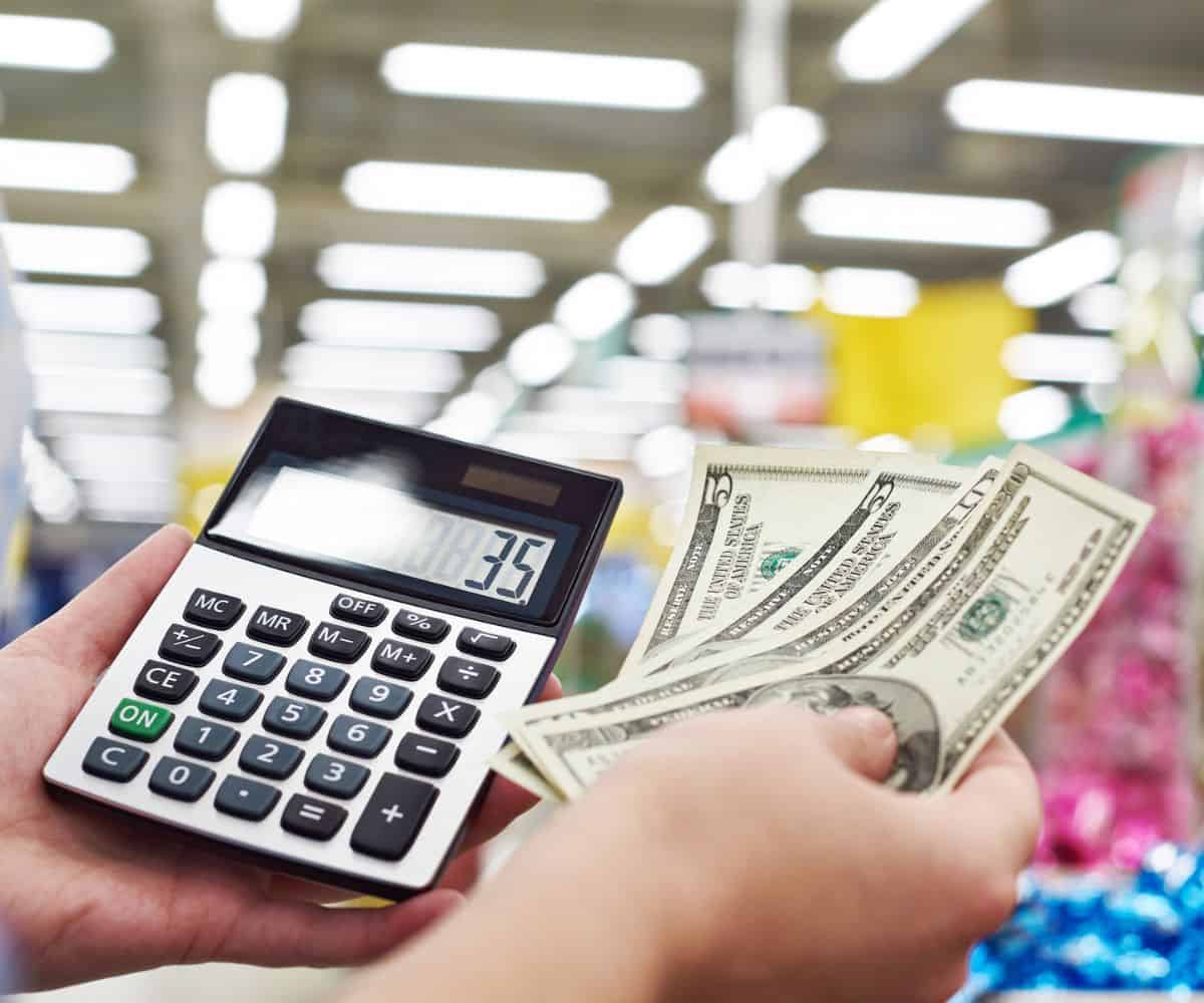 woman holding calculator, and dollars and five dollar bills