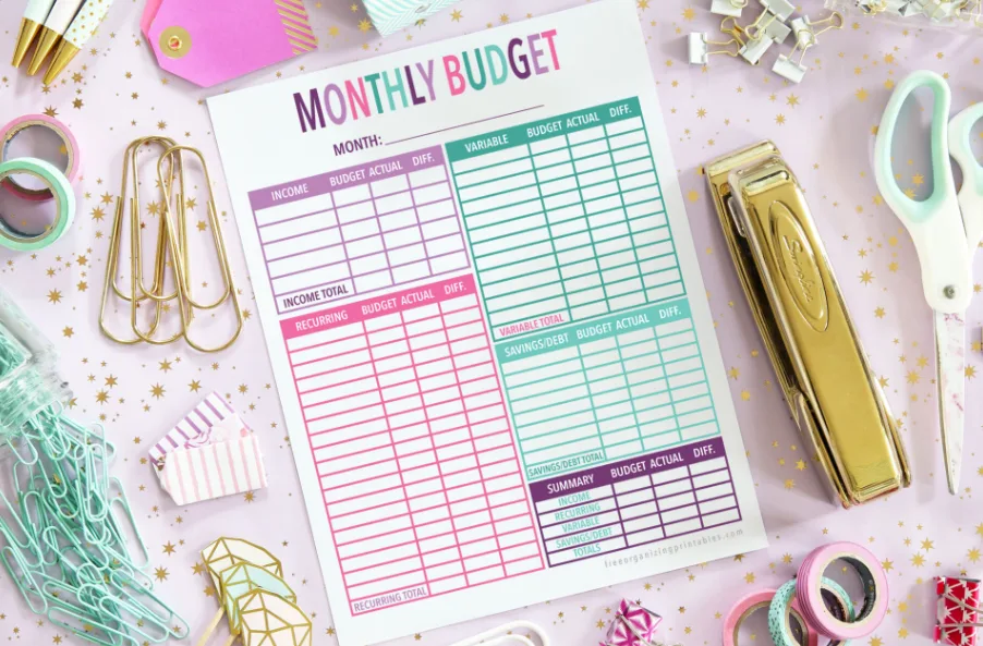 purple, pink, and teal monthly budget sheet as part of overall free printable budget binder, on desk with stationary tools