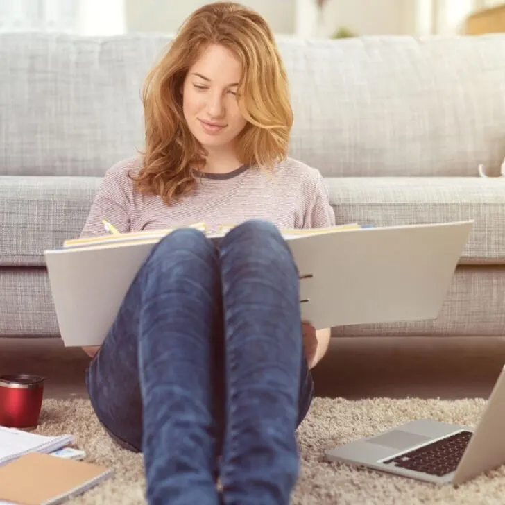 woman on floor with budget binder in lap, working