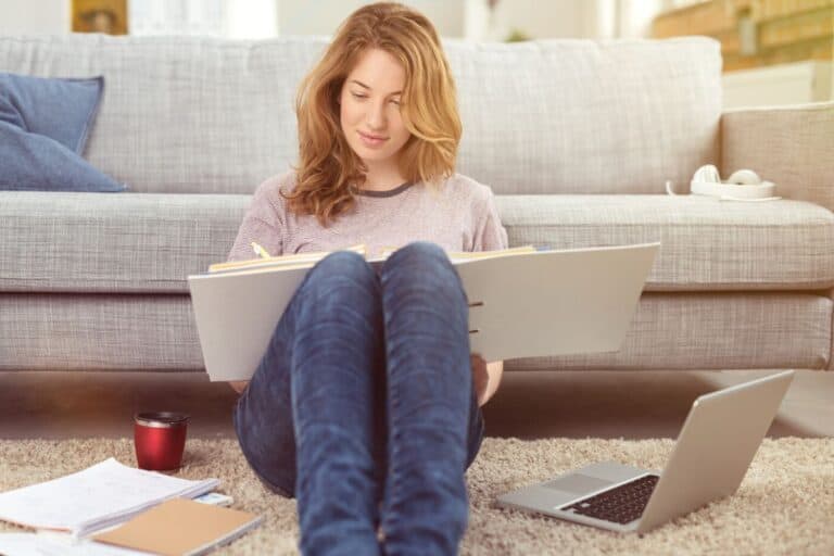 woman on floor with budget binder in lap, working