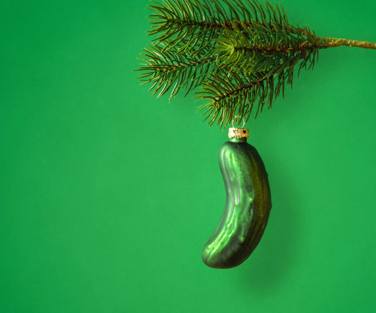 German Christmas pickle glass ornament on tree and green background