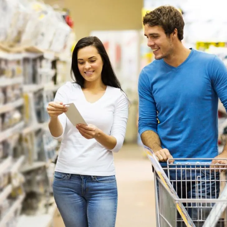 man and woman having fun in Dollar Store aisle with list