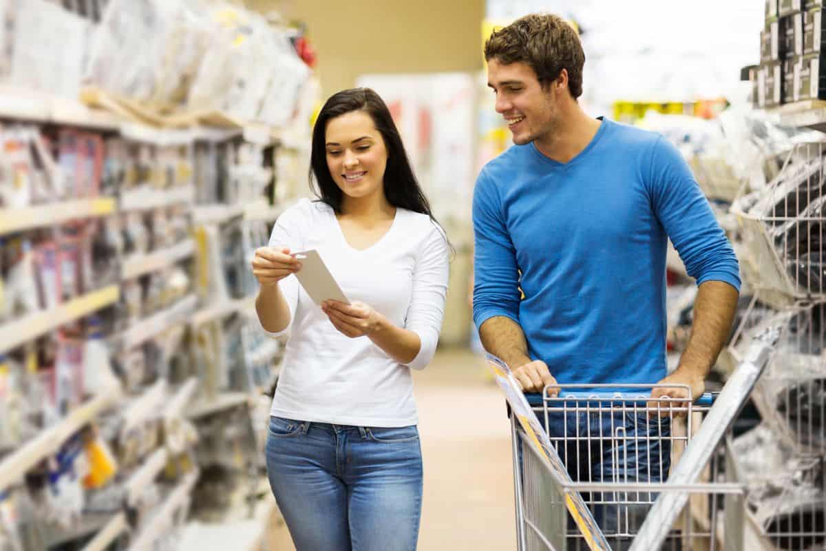 man and woman having fun in Dollar Store aisle with list