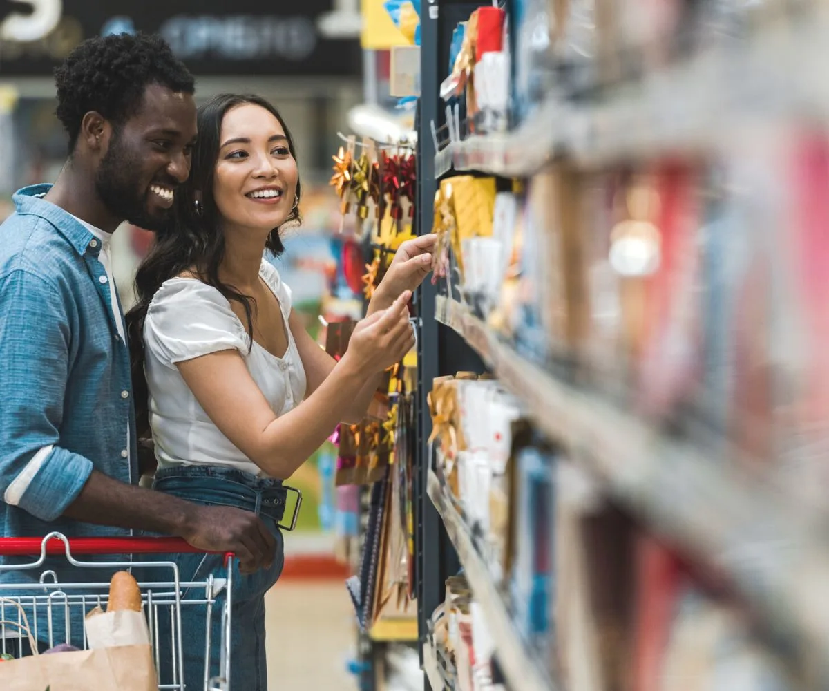 man holding woman in aisle of Dollar Store, both smiling and flirting