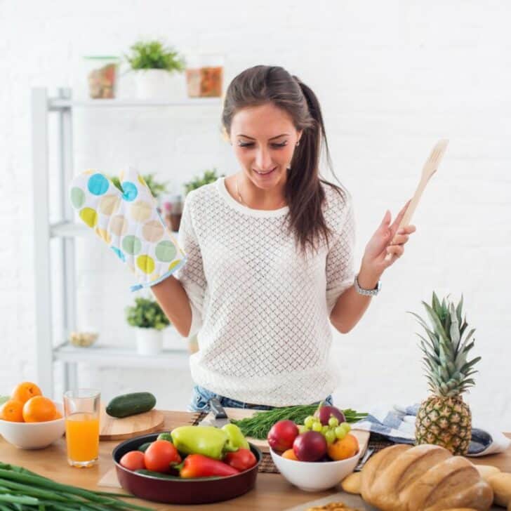 young woman with spatula and oven mitt cooking, smiling