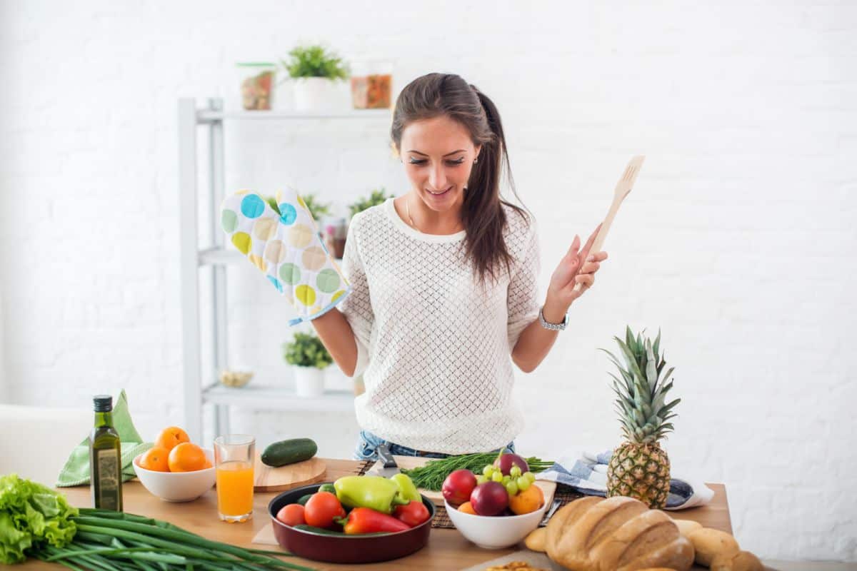 young woman with spatula and oven mitt cooking, smiling