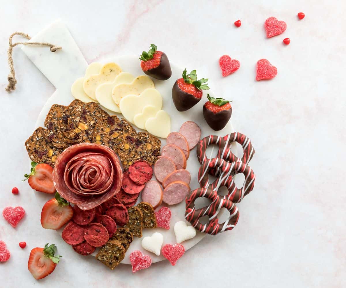 red and white and chocolate Valentine's charcuterie board on white marble background
