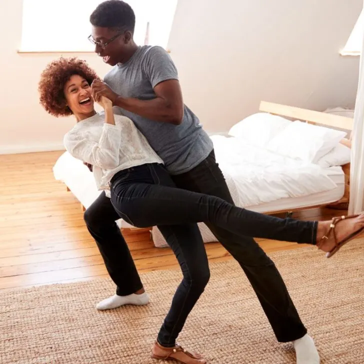 man and woman dancing and laughing in bedroom
