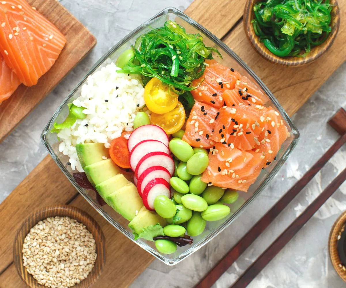 square glass bowl of salmon, edamame, avocado, rice, etc.
