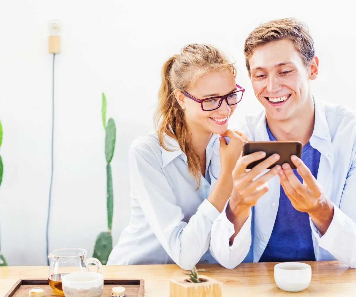 man and woman looking excitedly at iphone together