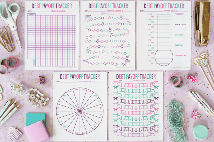 five purple, pink, and teal debt payoff trackers using percentages paid down, on pink dotted desk