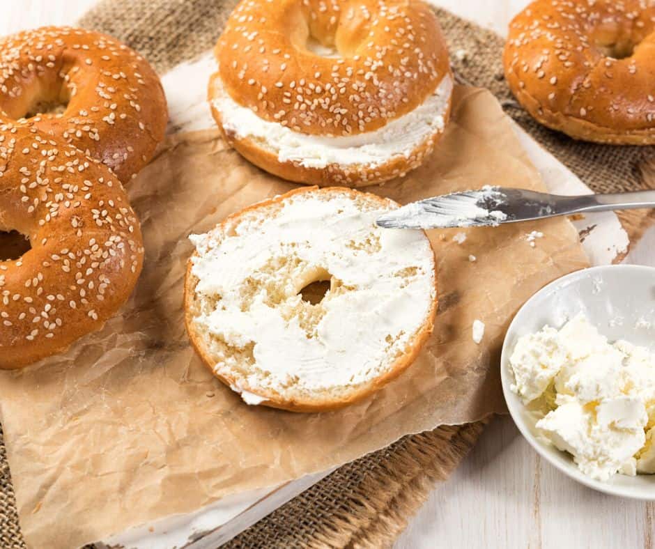spread of bagels and cream cheese with knife on brown paper
