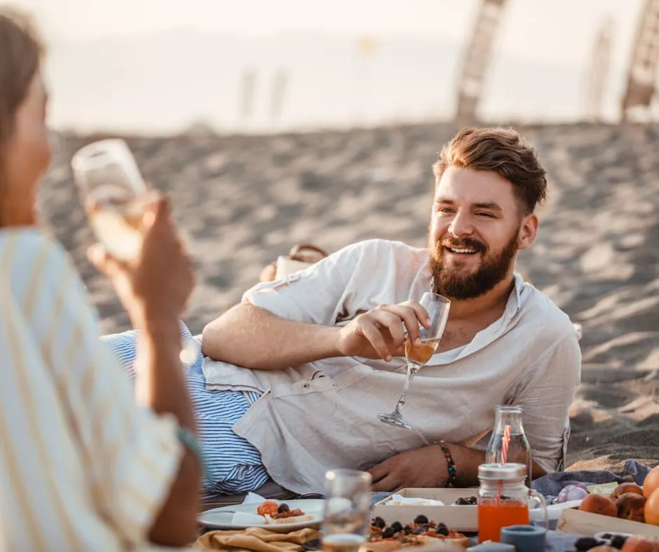 man and woman on beach in spring time with picnic