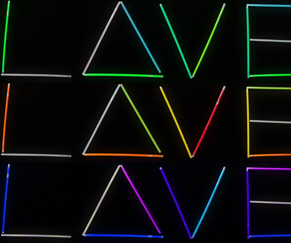 Love spelled out in glow sticks on black background, three times