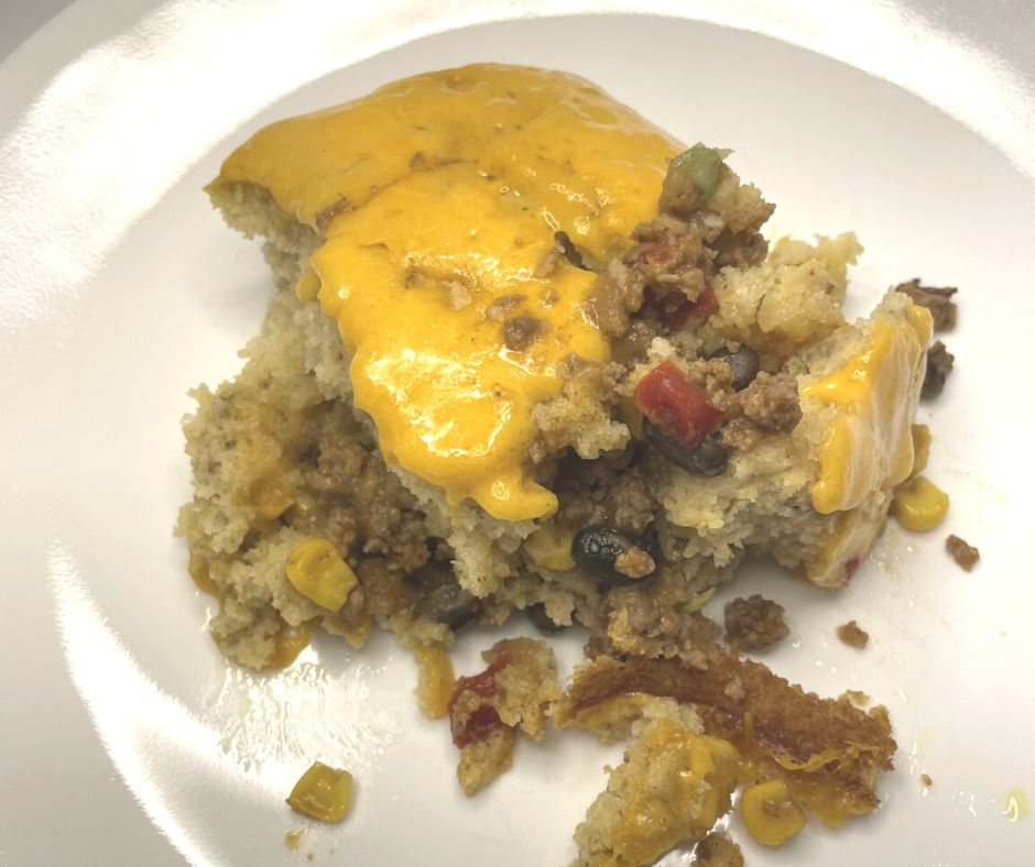 tamale pie with cornbread, melted cheese on top, sausage, beans, and corn