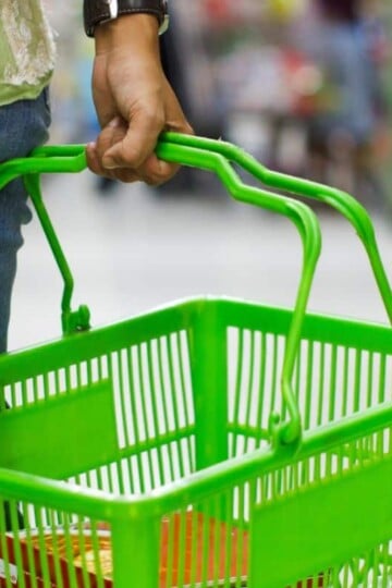 woman carrying dollar tree green food basket in store
