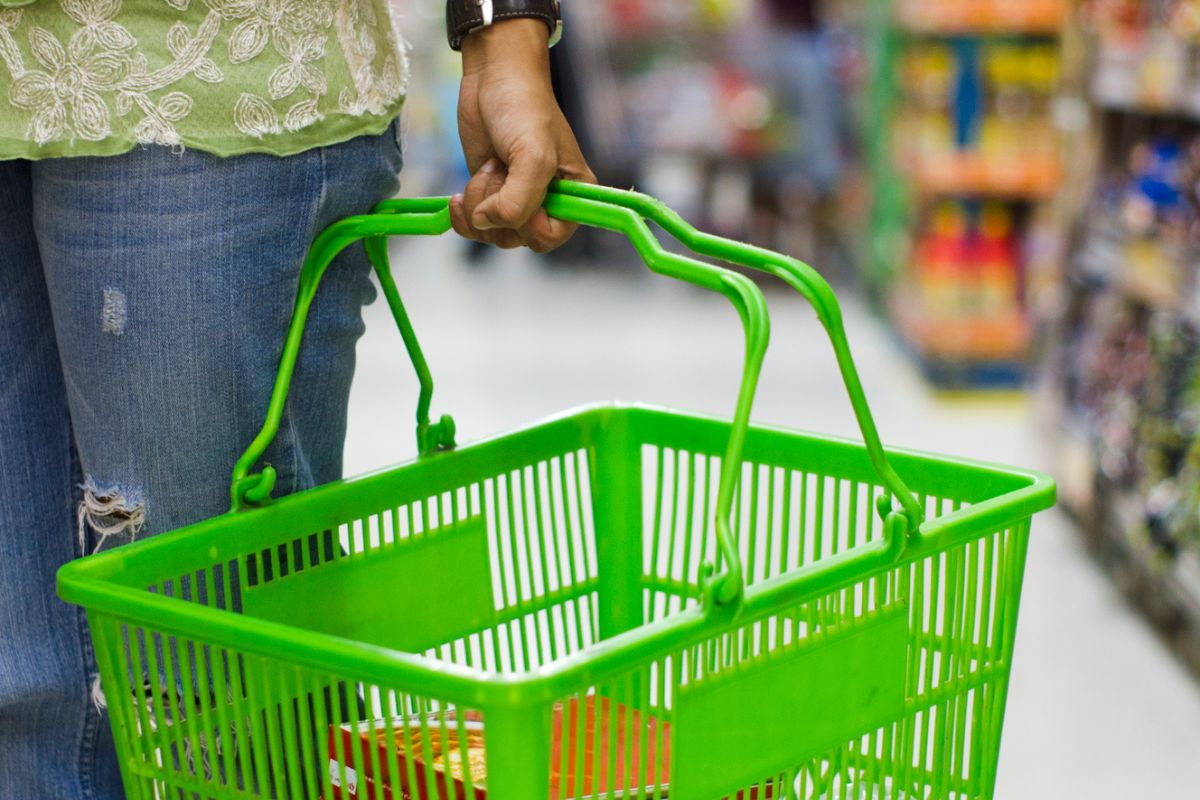 woman carrying dollar tree green food basket in store