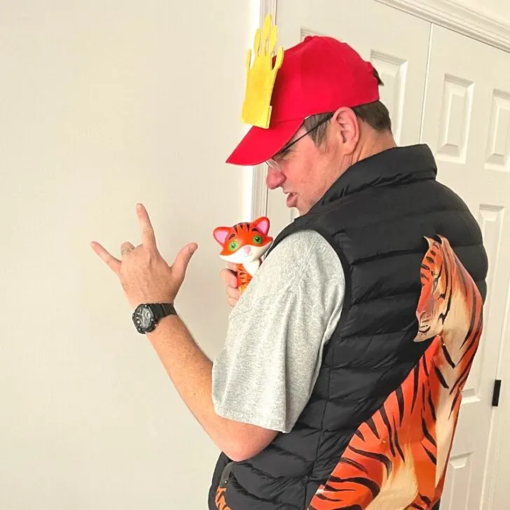 tiger king dollar store costume with tiger on back of black vest, red hat, etc.