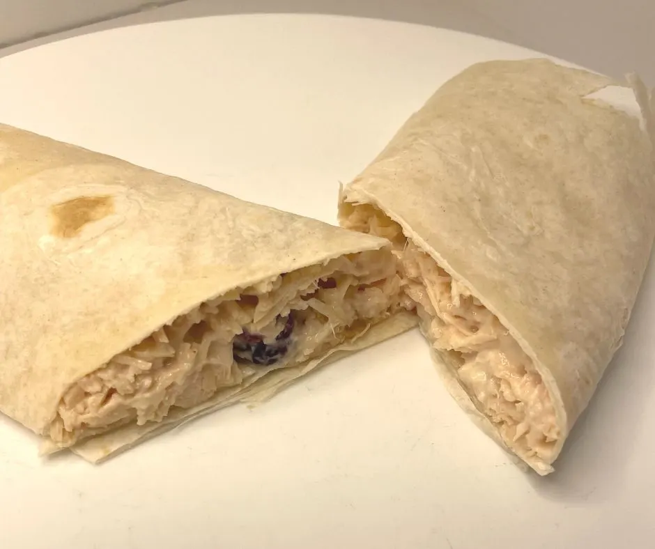 chicken salad wrap with cranberries and nuts sliced in half on white plate
