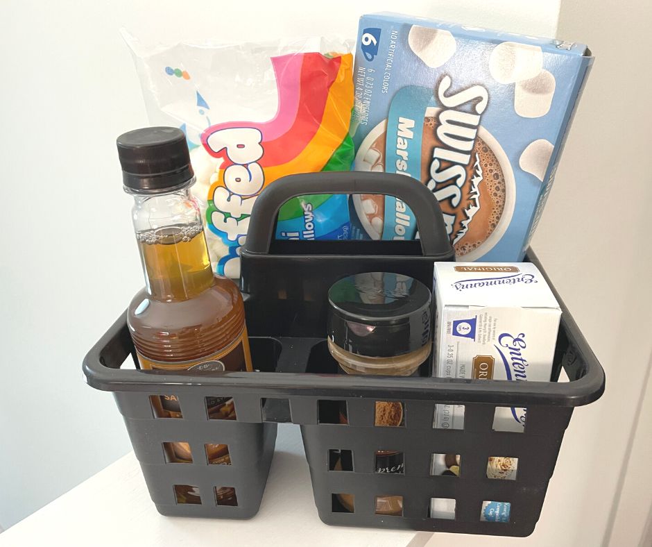 black shower caddy with mini marshmallows, cinnamon, hot chocolates, etc.