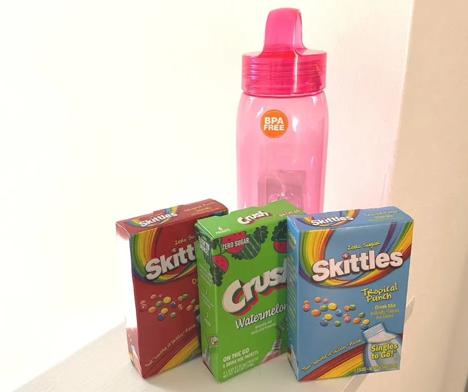 bpa-free pink water bottle with reusable straw set inside, three flavored drink boxes in front
