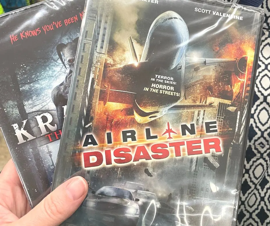 woman holding two movies from Dollar Tree - airline disaster and Krampus 