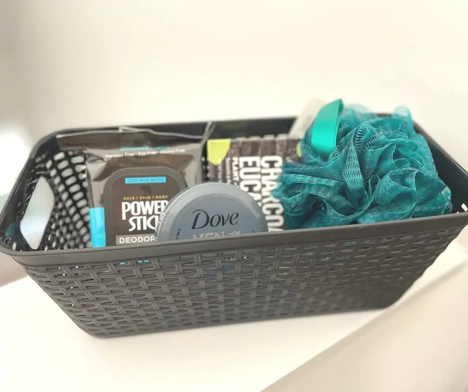 black rectangular basket with green pouf, and black packages of skincare/bathcare