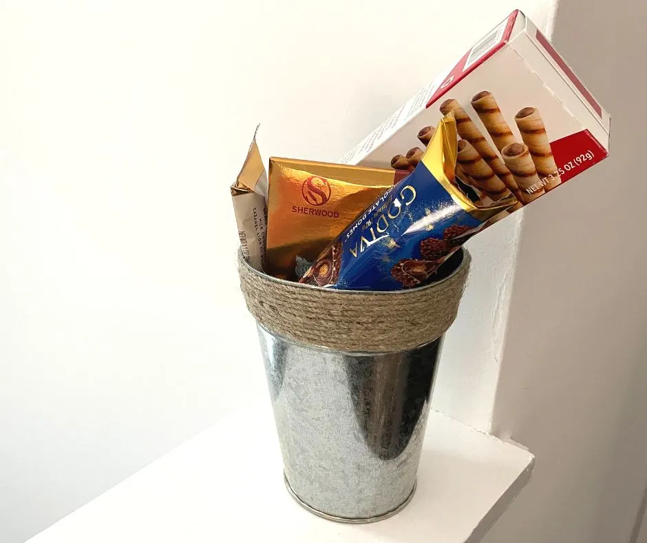 tin bucket with cord wrapping, filled with gourmet chocolate packages, white background