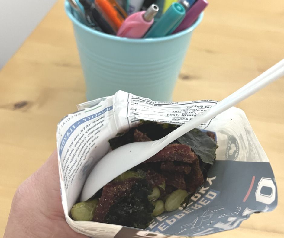 opened bag of beef jerky with white spoon, with seaweed and edamame pieces in it