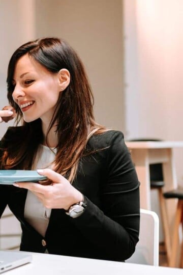woman eating healthy snack from Dollar Tree at desk, smiling