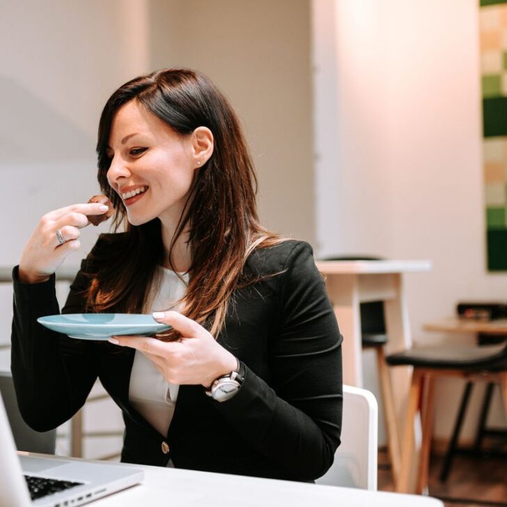 woman eating healthy snack from Dollar Tree at desk, smiling