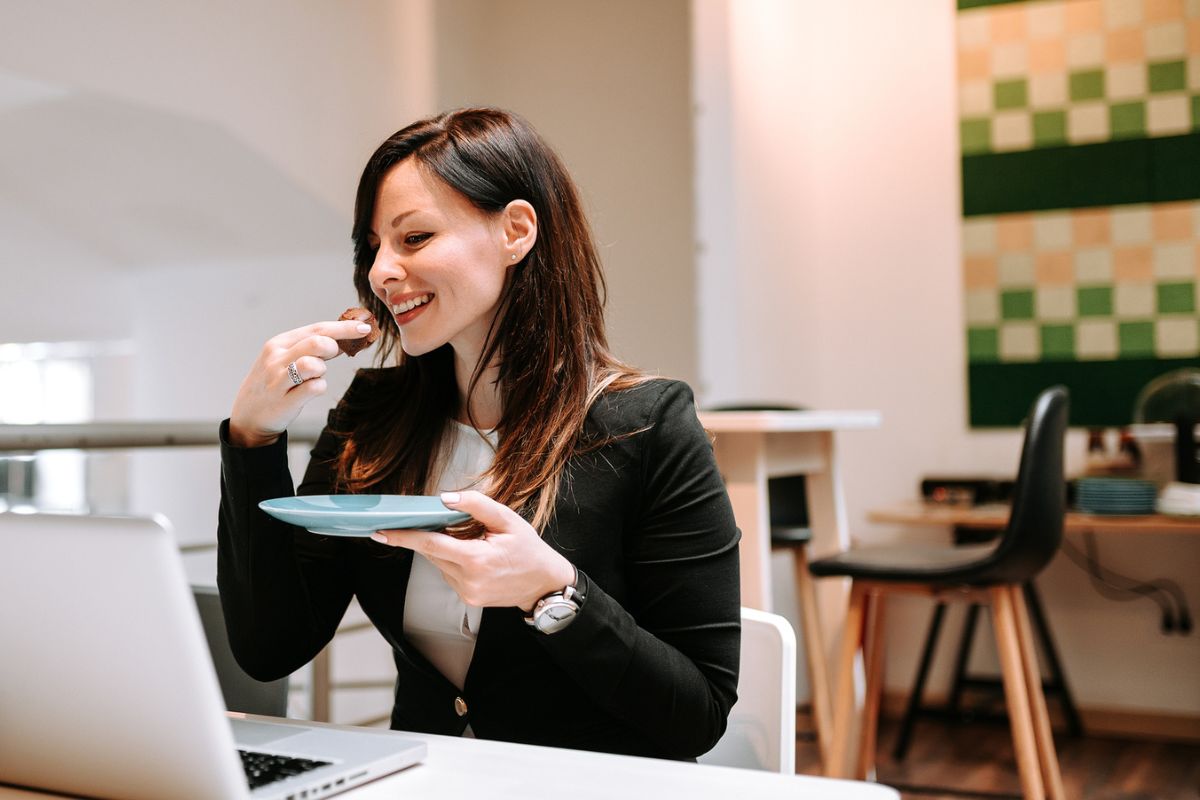 woman eating healthy snack from Dollar Tree at desk, smiling