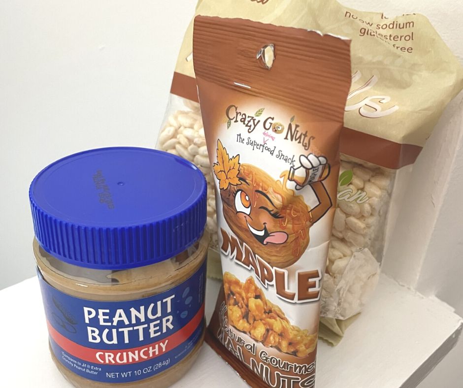 jar of peanut butter, package of maple walnuts, and package of rice sticks on white background