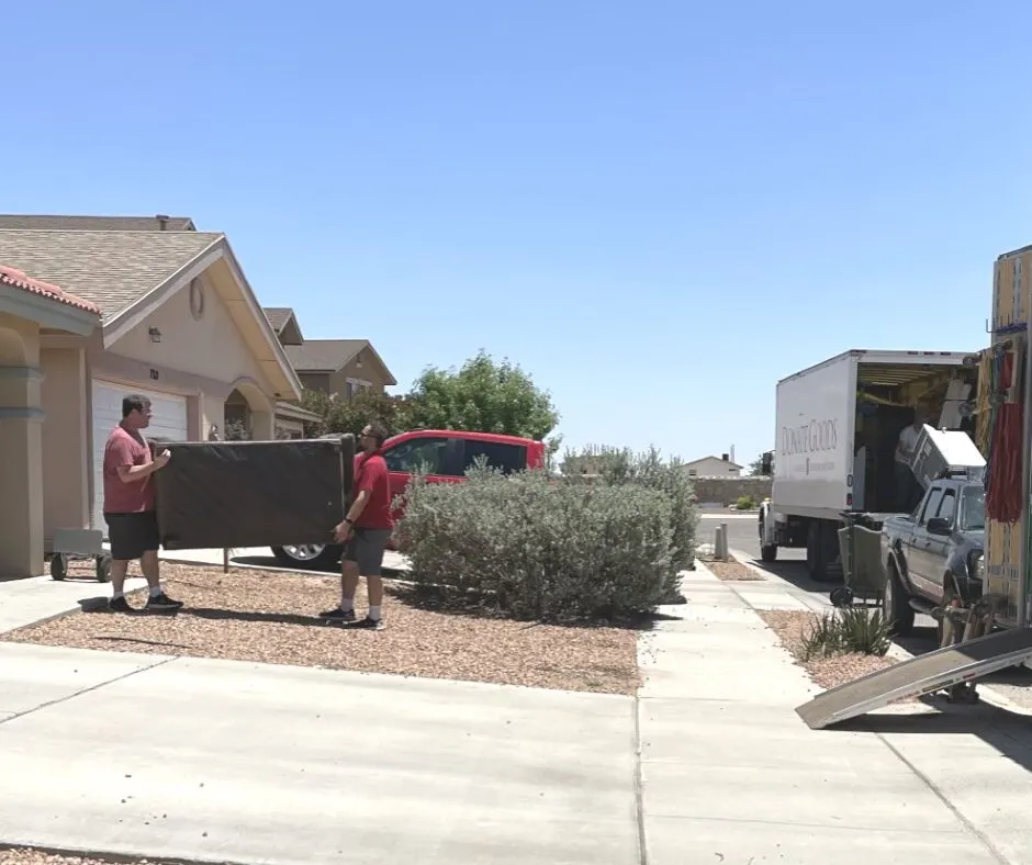 husband in red shirt carrying couch out of our home with Salvation Army person to their truck