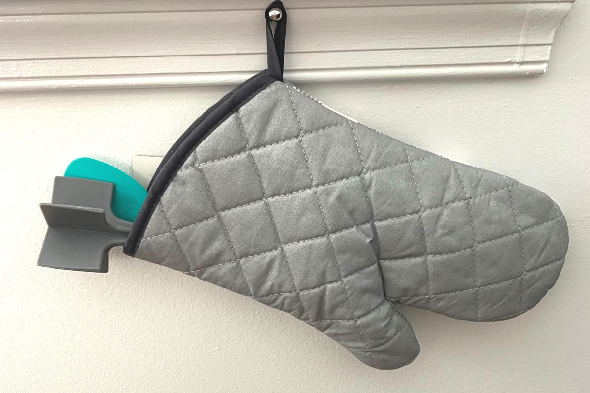 gray oven mitt with two kitchen tools out of top, hanging like stocking