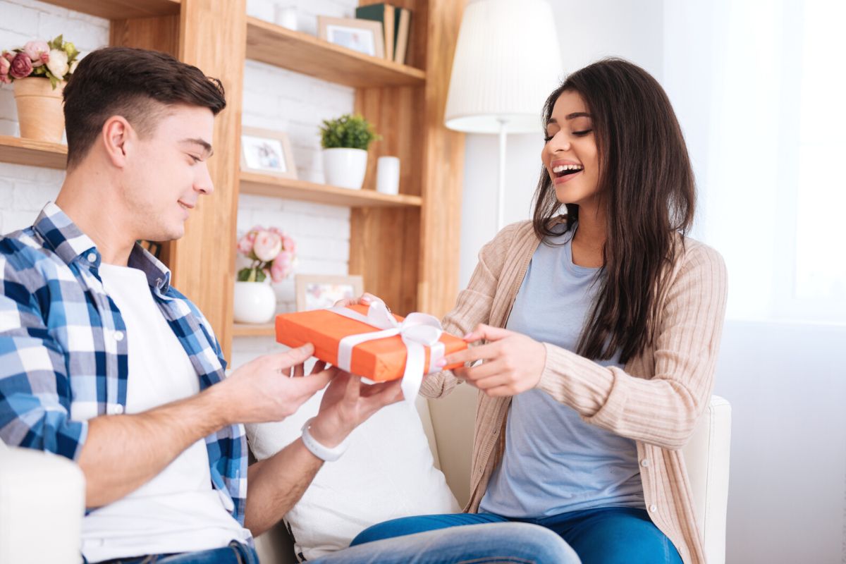 woman handing red gift wrapped box to man in plaid shirt
