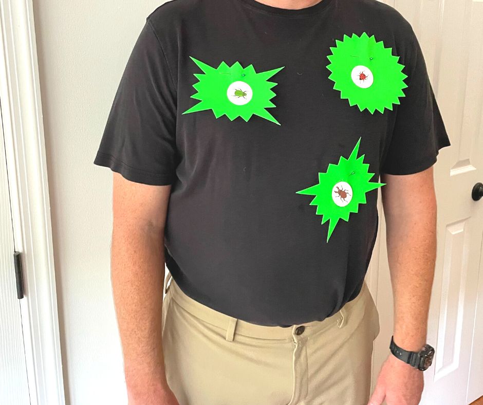 man in black shirt with neon green zap poster callouts, with three bugs on shirt