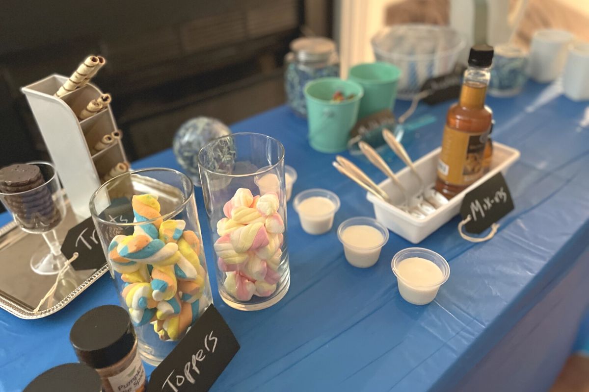 hot chocolate bar with lots of toppings and containers on blue tablecloth