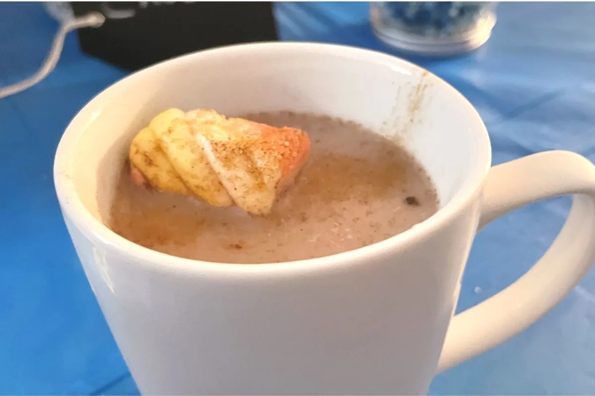white mug of hot chocolate with marshmallow, sprinkled with cinnamon and sugar