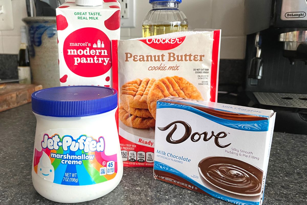 four ingredients: marshmallow fluff, milk, chocolate pudding, and peanut butter cookie mix on kitchen counter