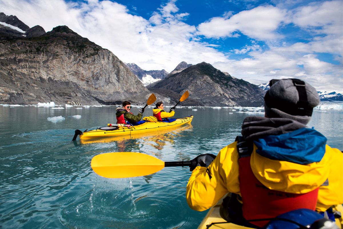 three kayakers in yellow jackets and yellow kayaks in Alaska