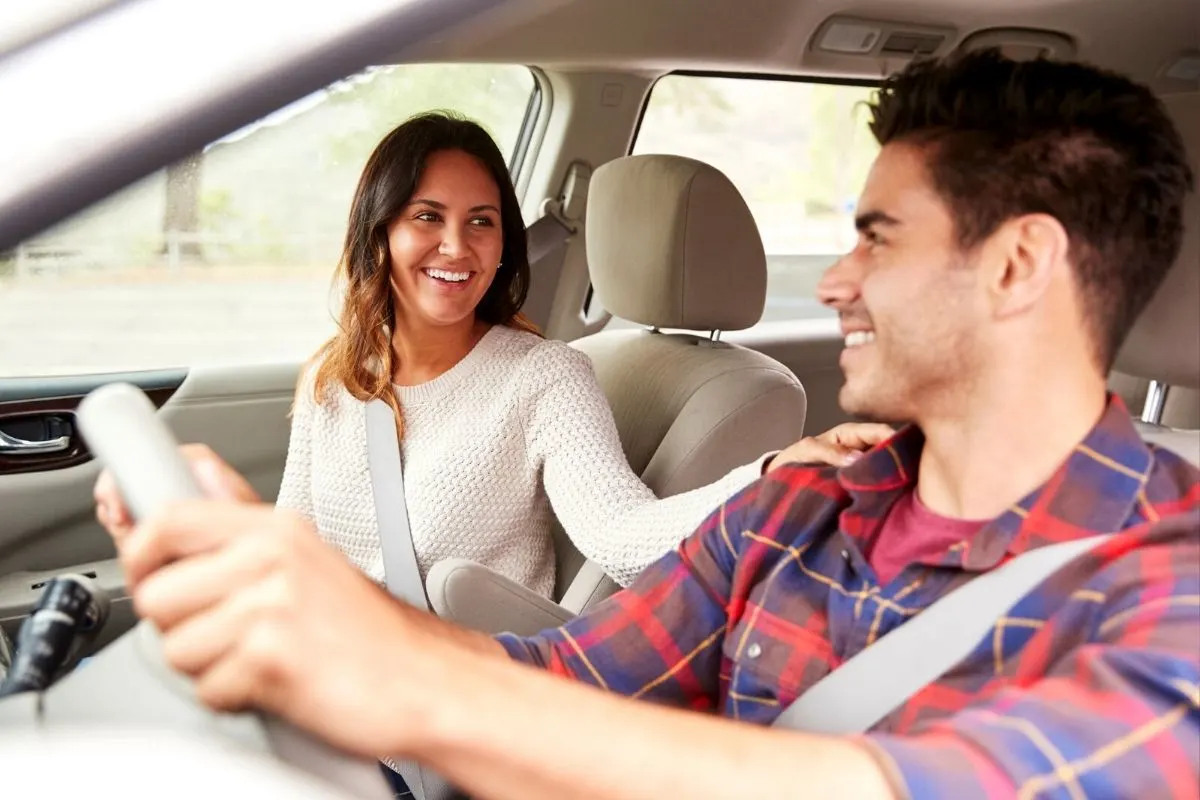 couple smiling knowingly at each other, driving in a car