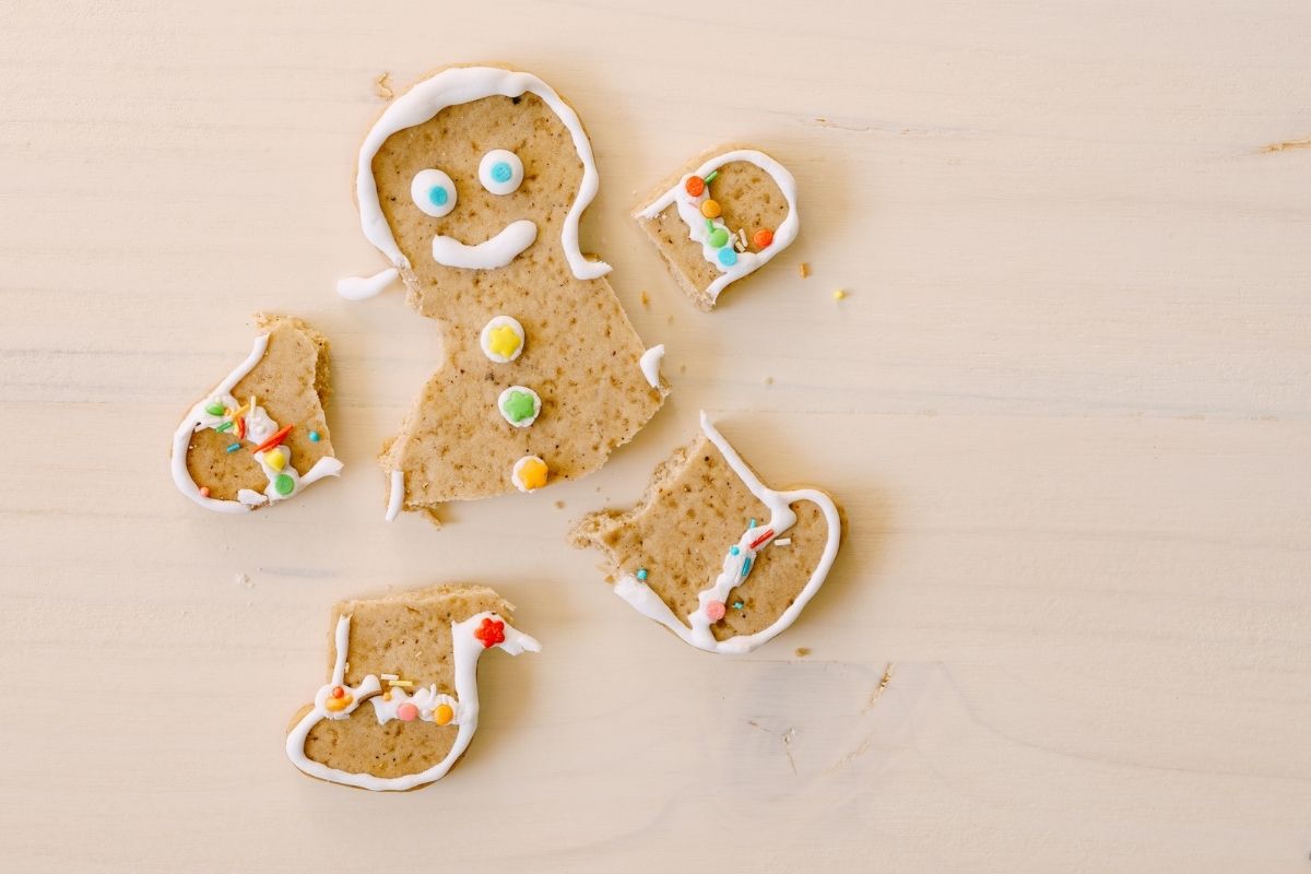 gingerbread cookie broken into limbs and body on wooden table