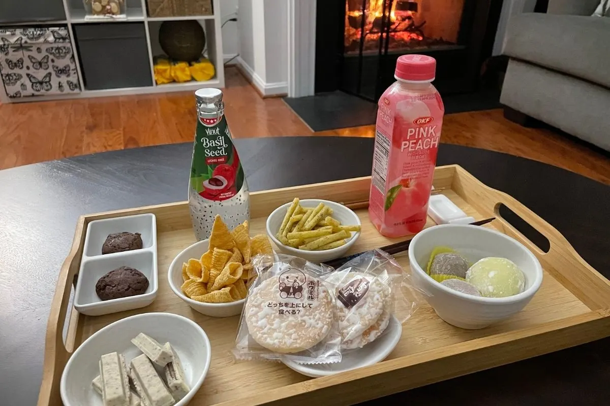 wooden tray filled with small dishes of Japanese snack foods and chopsticks, fire in fireplace