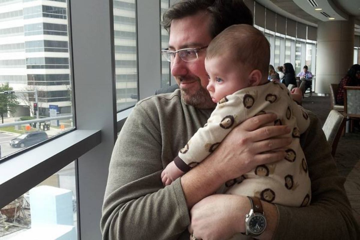 Daddy holding 3-month old baby while we eat lunch together on date at his work