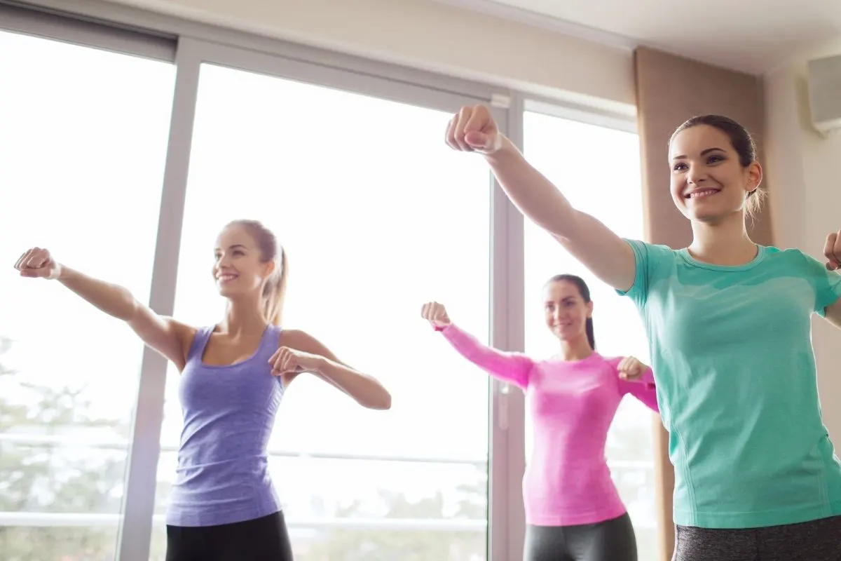 three women in workout clothes doing self-defense class at home