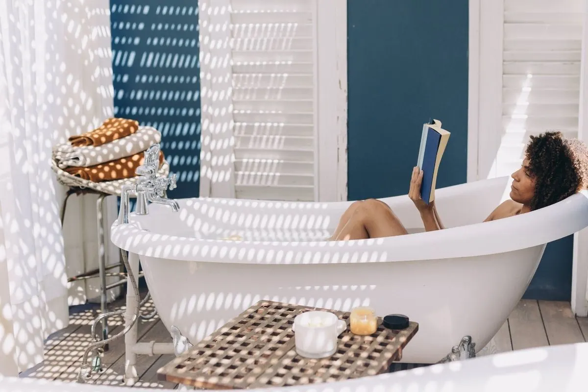 woman sitting in big white bathtub reading a book